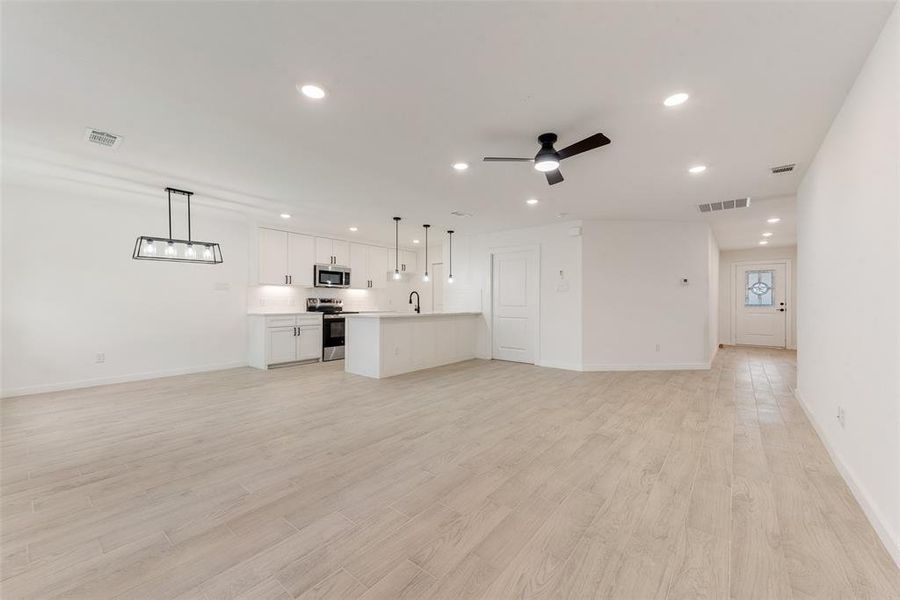 Unfurnished living room with sink, light hardwood / wood-style flooring, and ceiling fan