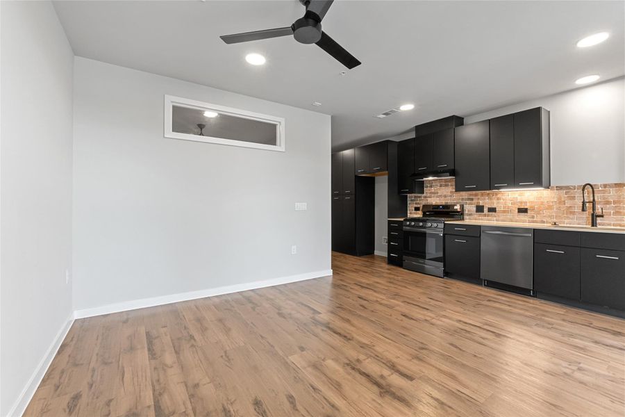 Kitchen featuring appliances with stainless steel finishes, dark cabinets, a ceiling fan, light wood-style floors, and recessed lighting