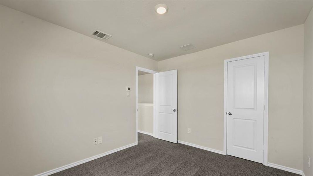 Room featuring neutral wall tones, gray carpeting, white trim, and two paneled doors with chrome hardware
