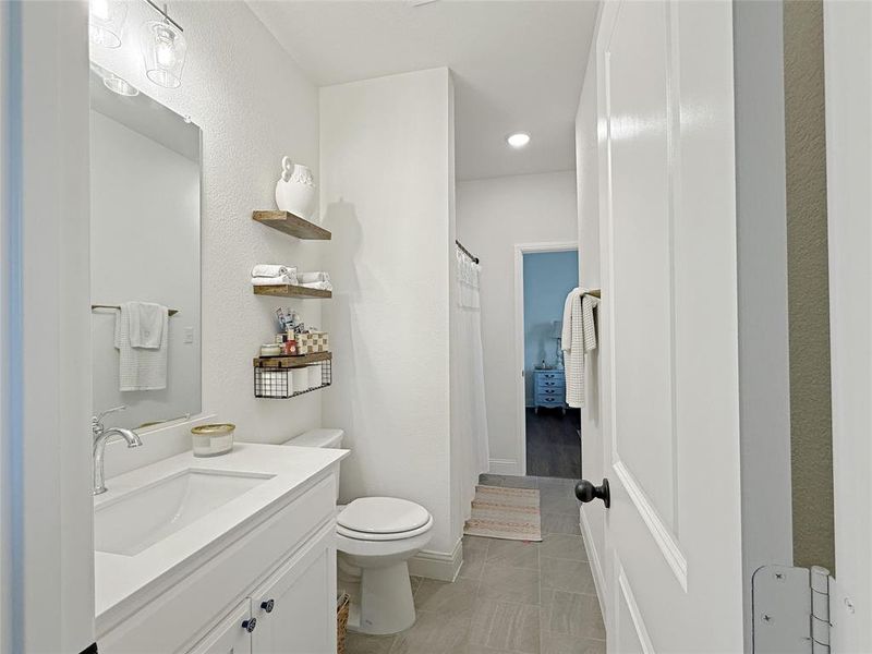 Bathroom featuring vanity, a textured wall, light tile patterned floors, and a shower with curtain Bathroom featuring vanity, a textured wall, light tile patterned floors, and a shower with curtain