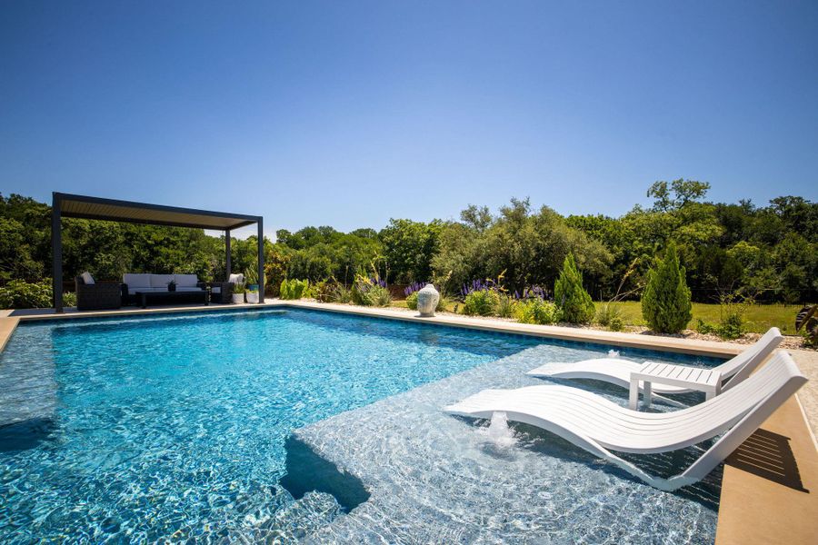 An inviting backyard oasis offers a sparkling pool with a tranquil covered patio retreat.