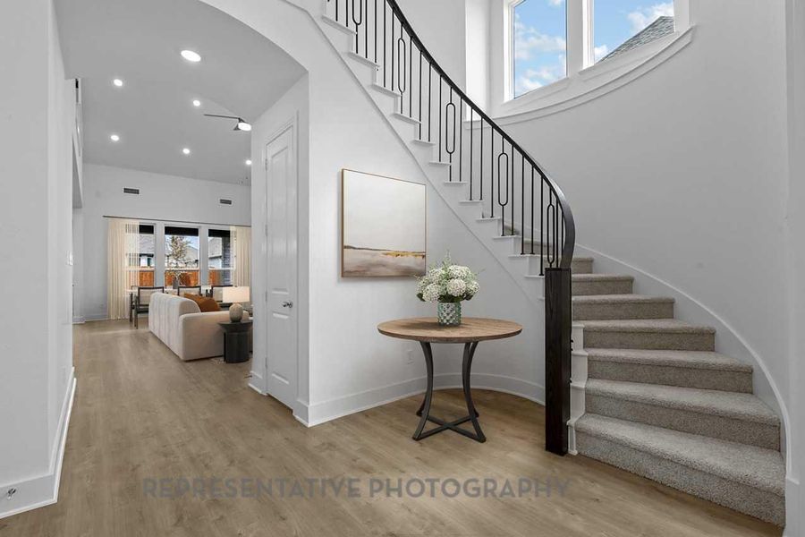 Staircase featuring a wealth of natural light, wood finished floors, and a towering ceiling Staircase featuring a wealth of natural light, wood finished floors, and a towering ceiling