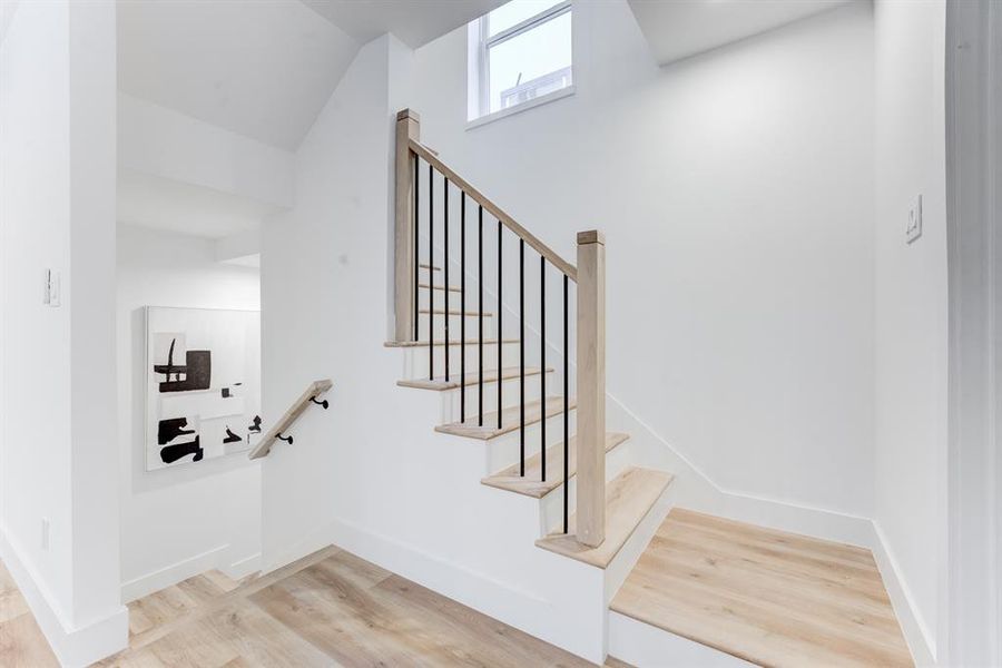 The stunning staircase and banister matches the luxury vinyl plank flooring throughout the home.