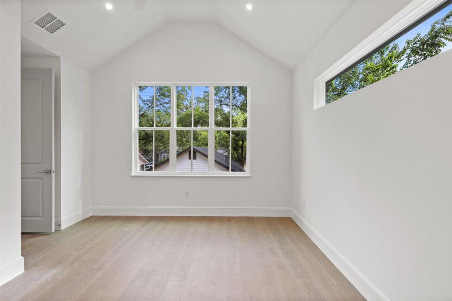 A naturally illuminated room features vaulted ceilings and light wood flooring, offering a tranquil retreat.