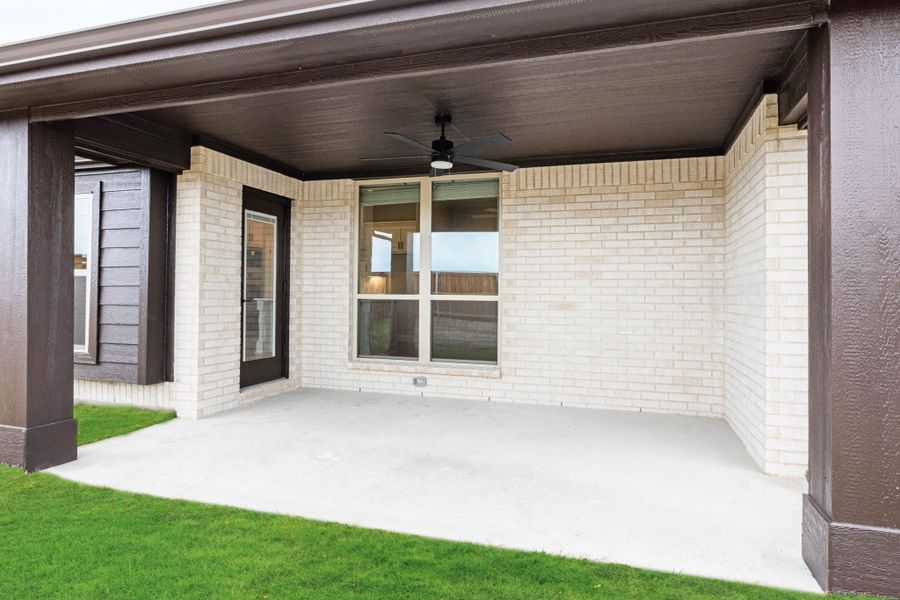 Covered back patio with ceiling fan, concrete floor, and cream brick exterior walls Covered back patio with ceiling fan, concrete floor, and cream brick exterior walls