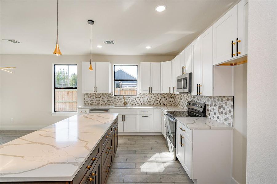 Kitchen with light stone countertops, white cabinetry, and stainless steel appliances