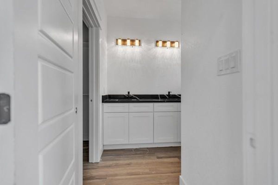 Full bath with double vanity and light wood-type flooring