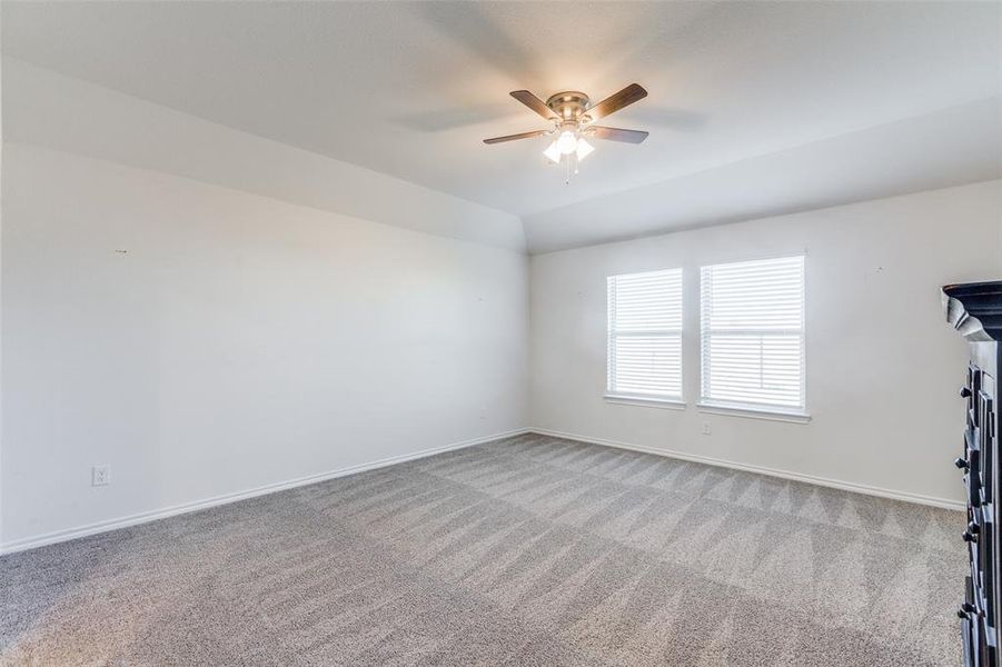 Carpeted empty room with vaulted ceiling and ceiling fan