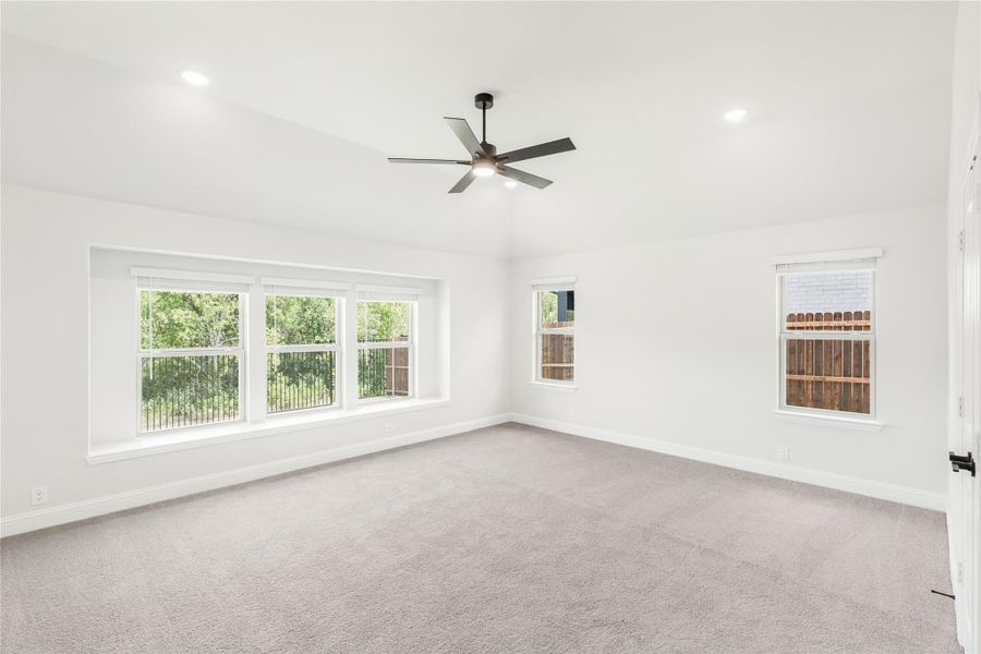 Empty bedroom with gray carpet, ceiling fan, white walls, and multiple windows Empty bedroom with gray carpet, ceiling fan, white walls, and multiple windows