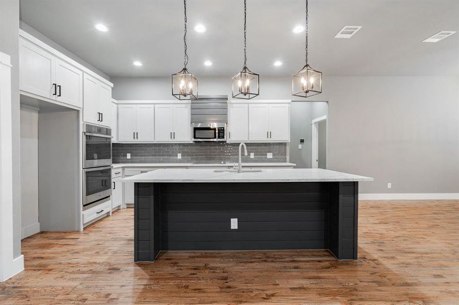 Kitchen featuring a sink, tasteful backsplash, stainless steel appliances, and white cabinets Kitchen featuring a sink, tasteful backsplash, stainless steel appliances, and white cabinets