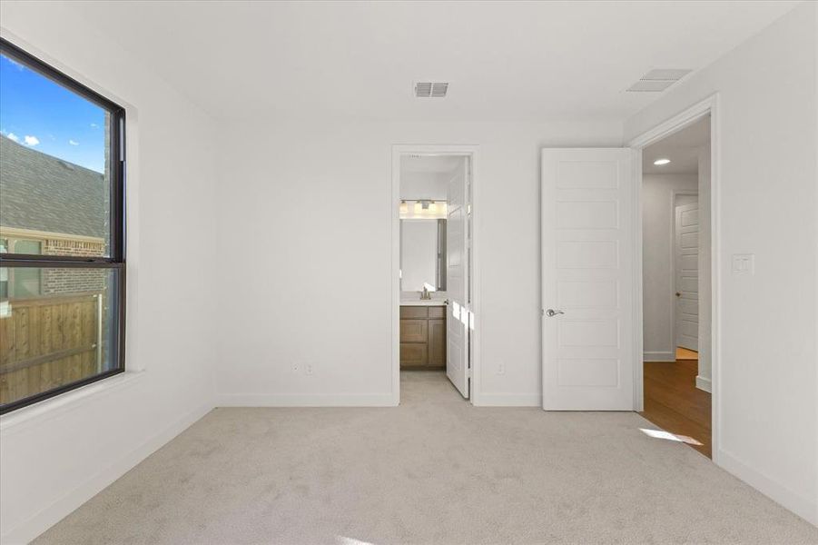 Unfurnished bedroom with light carpet and connected bathroom