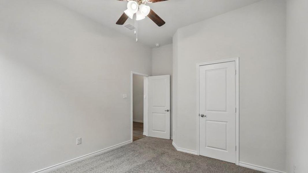 Carpeted room featuring a ceiling fan with light kit, painted white walls, white trim, and two white paneled doors