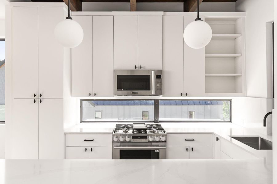 Kitchen featuring open shelves, stainless steel appliances, white cabinetry, light stone countertops, and pendant lighting