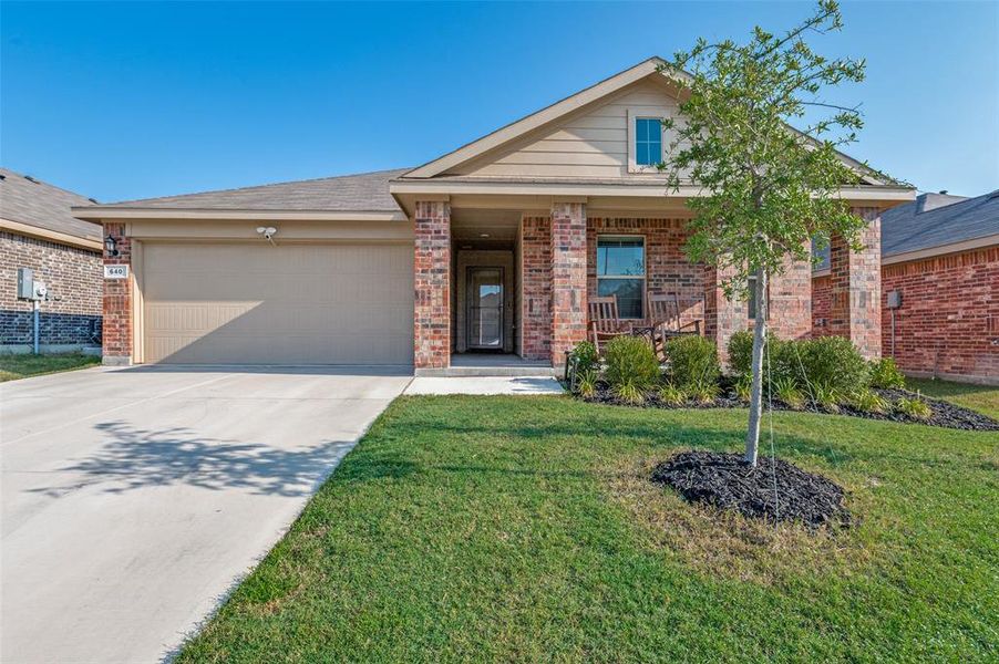 View of front facade featuring covered porch, concrete driveway, brick siding, an attached garage, and a front lawn