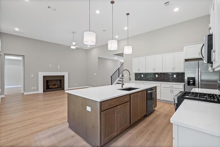 Open-concept living space featuring a central kitchen island with seating, dark wood-finish cabinetry, and white countertops Open-concept living space featuring a central kitchen island with seating, dark wood-finish cabinetry, and white countertops