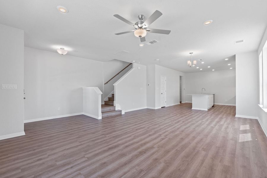 Unfurnished living room with ceiling fan, stairs, recessed lighting, and light wood-style floors