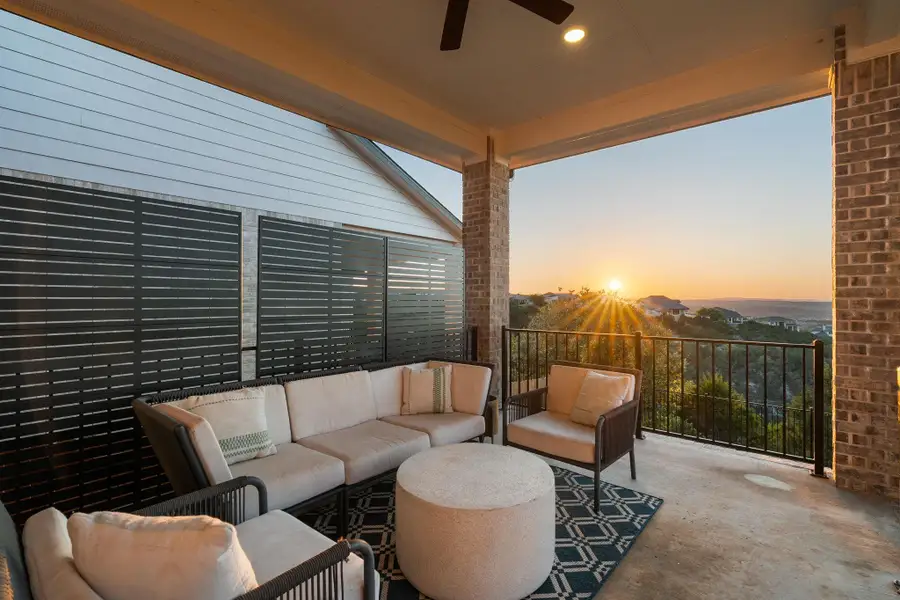 Spacious covered patio featuring brick columns, a black metal railing, overhead lighting, and a ceiling fan Spacious covered patio featuring brick columns, a black metal railing, overhead lighting, and a ceiling fan