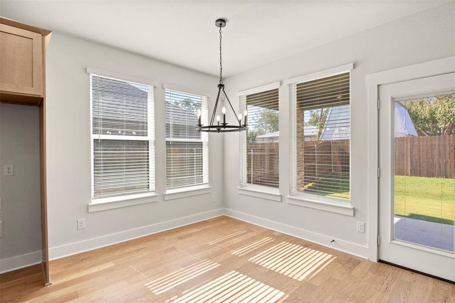 Unfurnished dining area featuring a chandelier and light wood-type flooring
