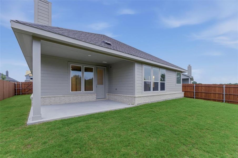 Spacious backyard featuring a covered patio, extensive lawn, and wood privacy fencing