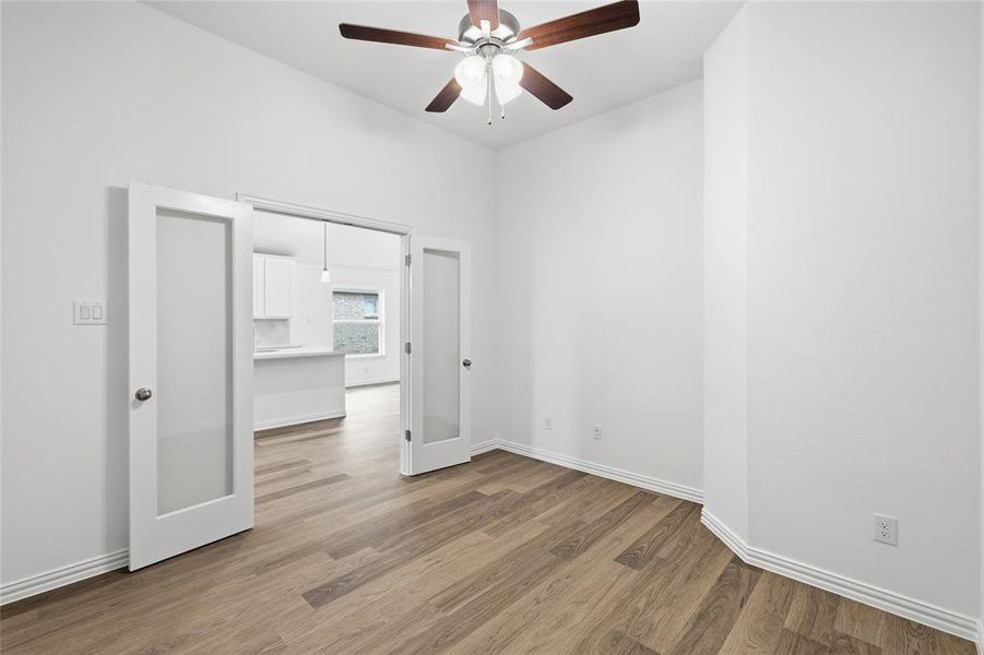 Room featuring wood-finish flooring, a ceiling fan, and white walls with baseboard molding