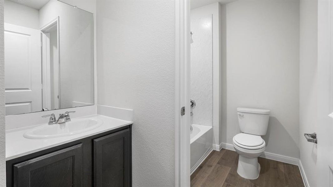 Full bath with vanity, dark wood-type flooring, shower / tub combination, and a textured wall