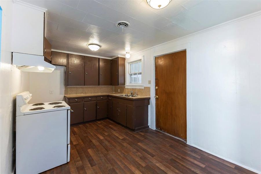 Kitchen with white range with electric stovetop, dark brown cabinets, under cabinet range hood, dark wood-type flooring, and light countertops Kitchen with white range with electric stovetop, dark brown cabinets, under cabinet range hood, dark wood-type flooring, and light countertops
