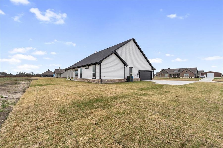 View of home's exterior featuring a garage, concrete driveway, a lawn, and brick siding