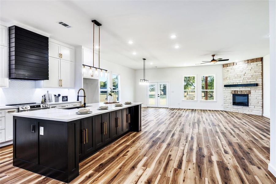 Kitchen featuring white cabinetry, french doors, decorative light fixtures, open floor plan, and light wood-type flooring