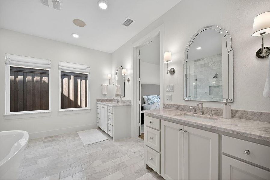 Ensuite bathroom featuring a stall shower, two vanities, a soaking tub, recessed lighting, and light marble finish flooring Ensuite bathroom featuring a stall shower, two vanities, a soaking tub, recessed lighting, and light marble finish flooring