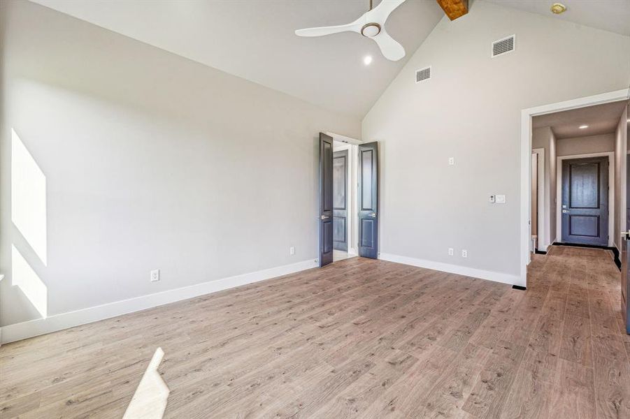 Unfurnished bedroom featuring beamed ceiling, light hardwood / wood-style flooring, ceiling fan, and high vaulted ceiling