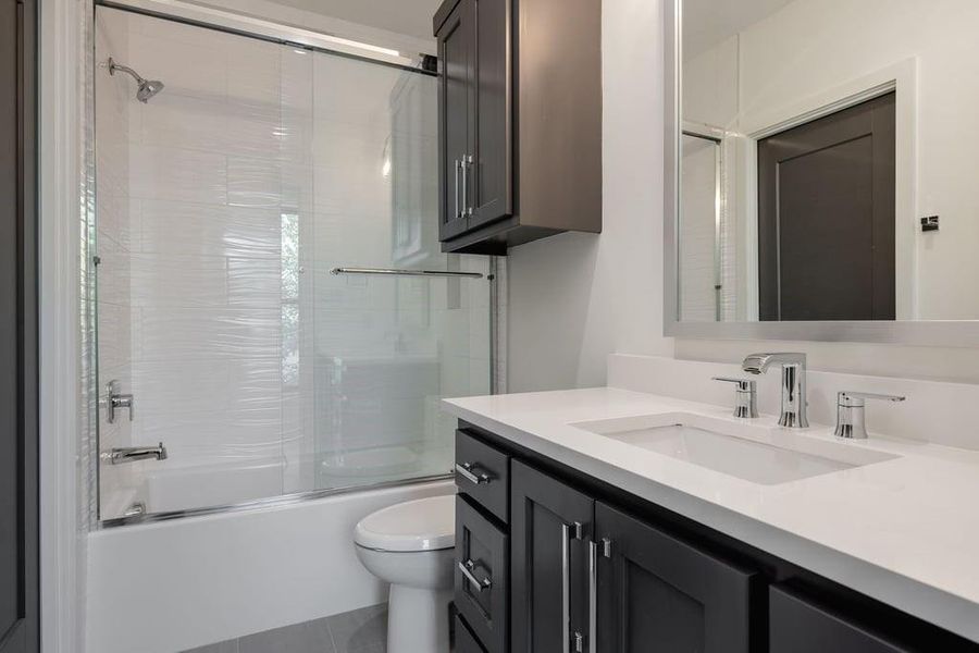 Full bathroom with tile patterned flooring, combined bath / shower with glass door, toilet, and vanity