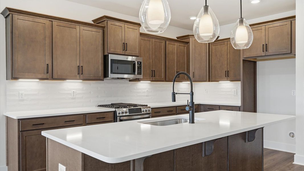 Tasteful kitchen with oversized island and stylish pendant lighting—crafted to high standards located at Iris Meadows Tasteful kitchen with oversized island and stylish pendant lighting—crafted to high standards located at Iris Meadows