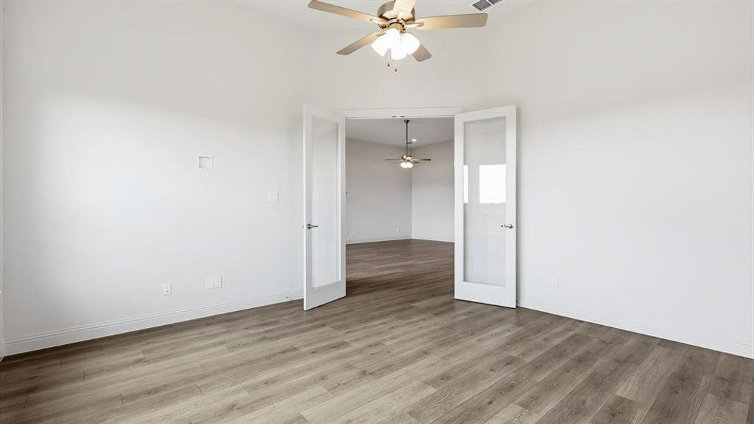 Spacious room featuring wood-finish flooring, vaulted ceiling, and a ceiling fan