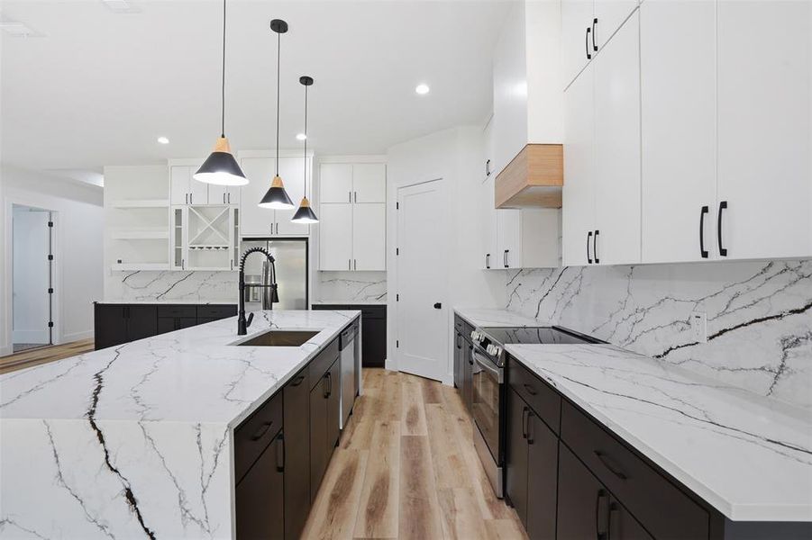 Modern kitchen featuring an expansive island with a built-in sink and pendant lighting