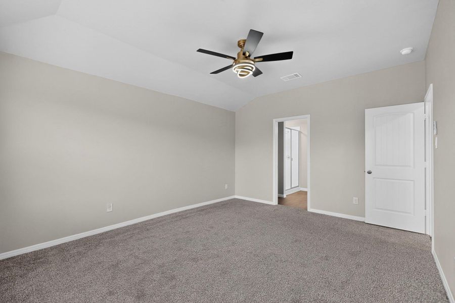 Plush carpeting anchors this spacious bedroom featuring vaulted ceilings.