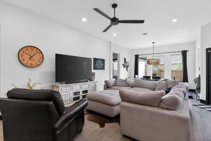 Spacious open-concept living area featuring light-toned walls, recessed lighting, and a modern ceiling fan