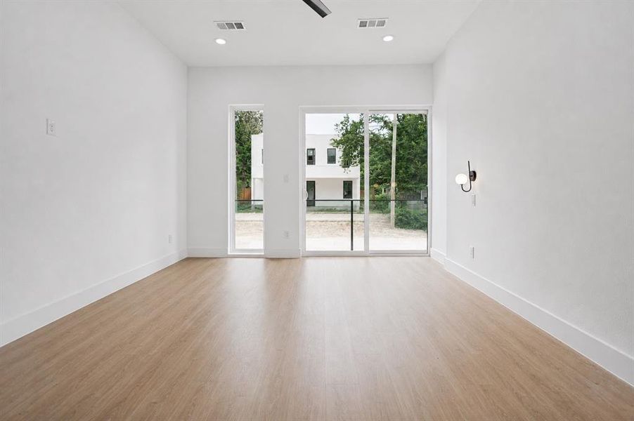 Spacious room featuring wood-finish flooring, white baseboards, and bright white walls