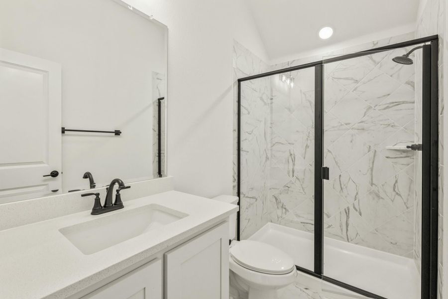 Bathroom with white vanity, black fixtures, and glass shower with marble-look tile walls Bathroom with white vanity, black fixtures, and glass shower with marble-look tile walls