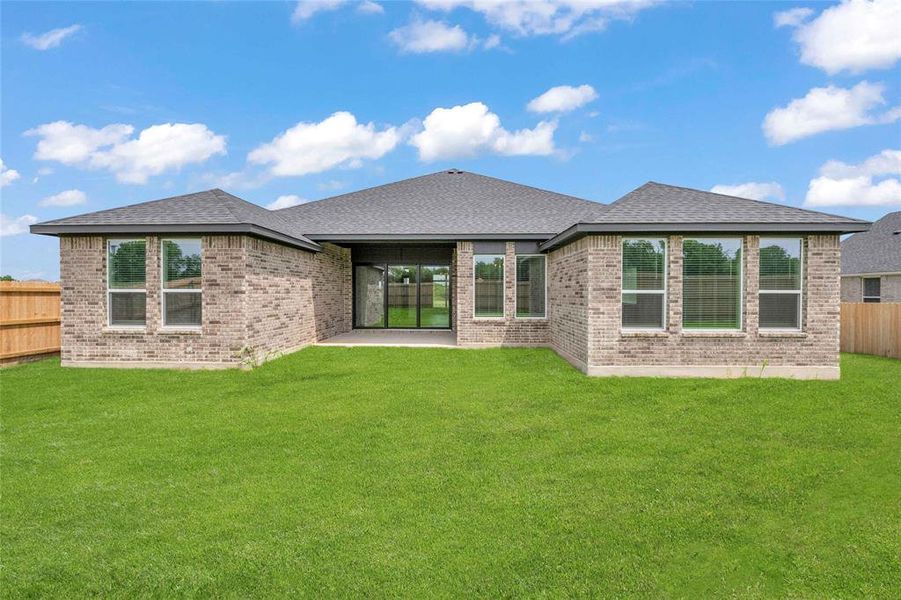 Rear view of property with a lawn, brick siding, a fenced backyard, and roof with shingles