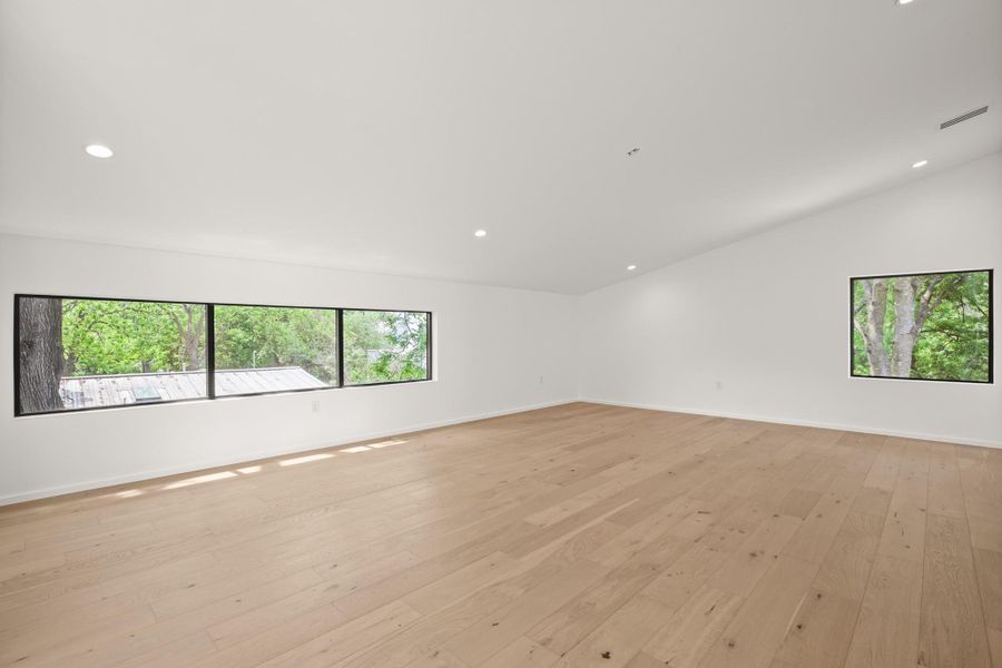 Empty room with light wood-style flooring and recessed lighting