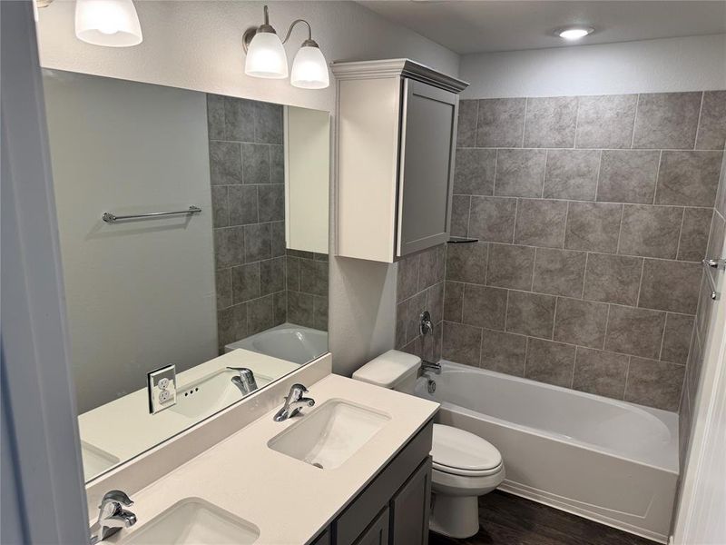 Bathroom featuring double vanity, dark wood-style flooring, and shower / tub combination
