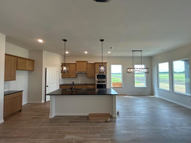 Open-concept kitchen and living area featuring wood-finish flooring, recessed lighting, and a kitchen island with pendant lighting