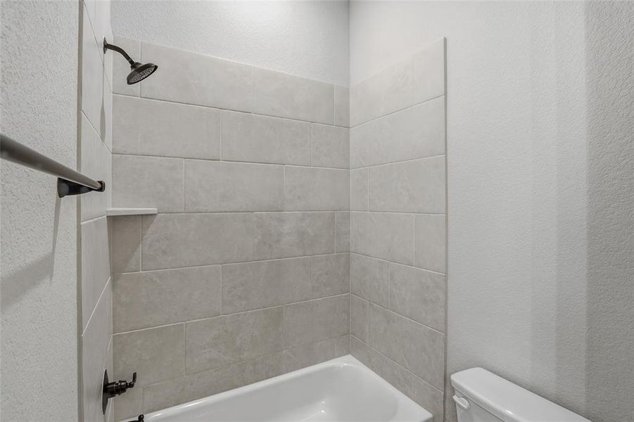 Full bath featuring a textured wall and bathing tub / shower combination
