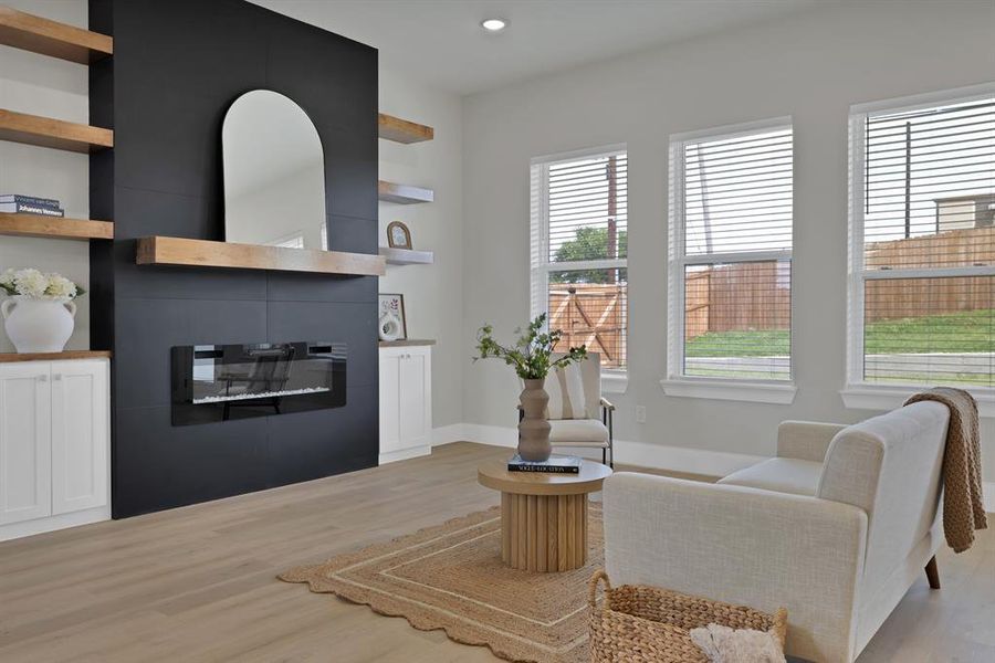 Living area with a glass covered fireplace, light wood-style flooring, recessed lighting, and baseboards Living area with a glass covered fireplace, light wood-style flooring, recessed lighting, and baseboards