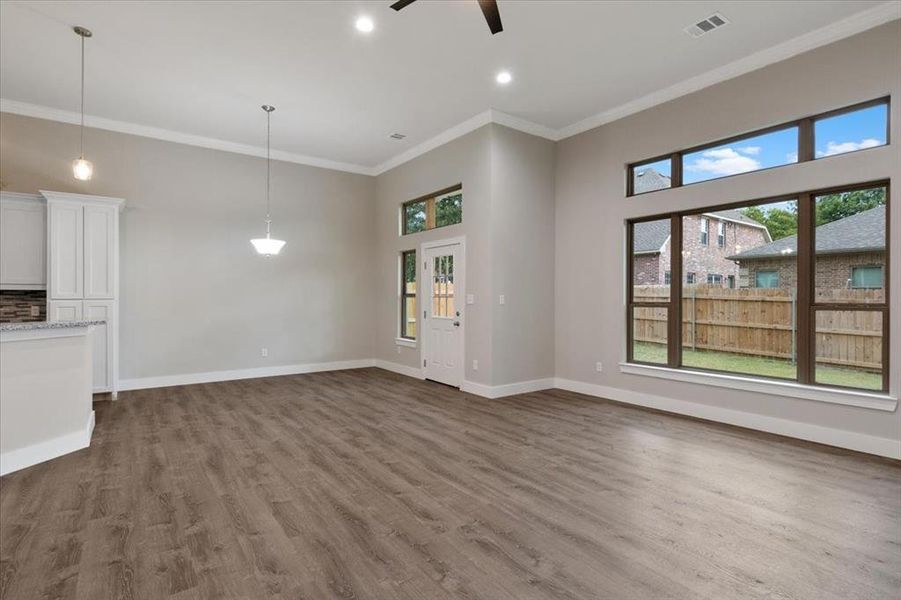 Unfurnished living room featuring ceiling fan, crown molding, hardwood / wood-style flooring, and a high ceiling