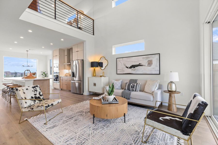 Living room featuring healthy amount of natural light, light wood-style floors, a high ceiling, and recessed lighting