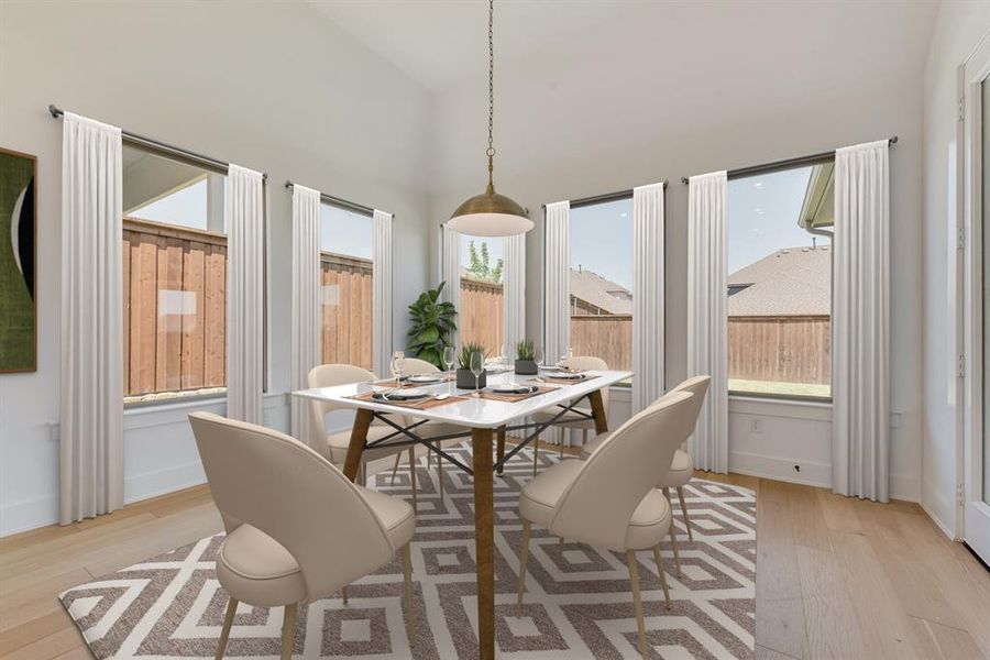 Dining space featuring light wood-type flooring, plenty of natural light, and high vaulted ceiling