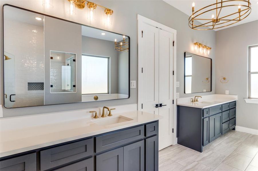 Bathroom featuring a chandelier, a shower stall, two vanities, plenty of natural light, and recessed lighting Bathroom featuring a chandelier, a shower stall, two vanities, plenty of natural light, and recessed lighting