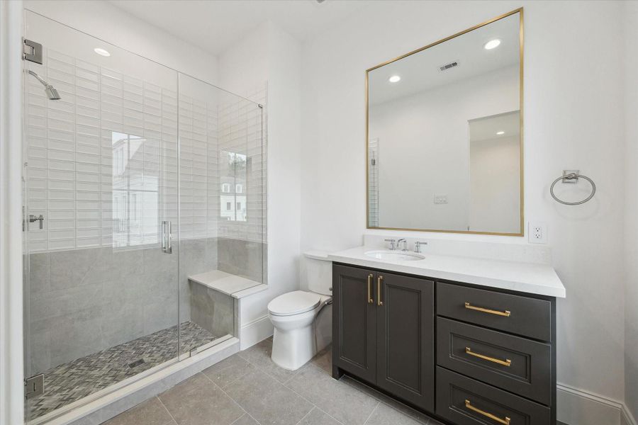 En-suite bathroom features a sleek, glass-encased shower, Quartz counters and additional counter and storage space.