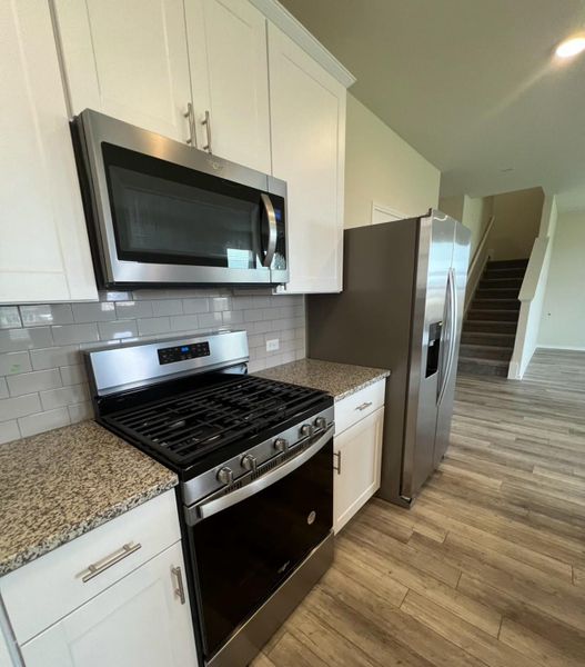 The contemporary kitchen features stainless steel appliances, ice maker, and durable granite countertops, offering seamless living.